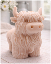 Load image into Gallery viewer, A detailed handmade vegan soap in a sculpted in the shape of a highland cow with characteristic long, wavy fur, horns, and a friendly face, displayed on a light wooden surface