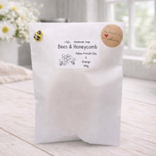 Load image into Gallery viewer, White soap packaging with a label on a light wooden surface, surrounded by flowers.