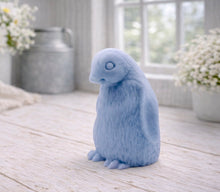 Load image into Gallery viewer, handmade vegan soap in the shape of a realistic young penguin sculpture, featuring a soft downy fur texture and a gentle expression, displayed in a bright farmhouse decor setting.