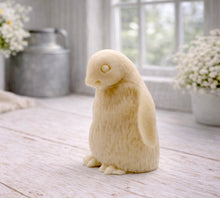 Load image into Gallery viewer, handmade vegan soap in the shape of a realistic young penguin sculpture, featuring a soft downy fur texture and a gentle expression, displayed in a bright farmhouse decor setting.