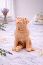 Load image into Gallery viewer, handmade vegan soap in the shape of a realistic sitting pug dog, looking upwards with detailed fur texture, displayed in a spa-like setting with lavender and a lit candle.