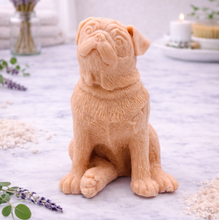 Load image into Gallery viewer, handmade vegan soap in the shape of a realistic sitting pug dog, looking upwards with detailed fur texture, displayed in a spa-like setting with lavender and a lit candle.