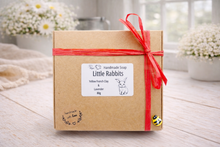 Load image into Gallery viewer, Handmade soap packaging with a red ribbon on a wooden surface