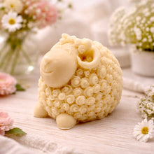 Load image into Gallery viewer, handmade vegan soap in the shape of a realistic smiling ram with curved horns and detailed curly wool texture, displayed on a rustic wooden surface with lavender and white flowers.
