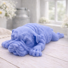 Load image into Gallery viewer, A highly detailed handmade vegan soap in a sophisticated slate-grey tone, sculpted in the shape of a Shar Pei puppy lying flat on its stomach with its head resting on its paws, featuring realistic deep skin folds and wrinkles.