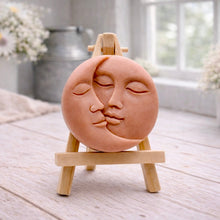 Load image into Gallery viewer, handmade vegan soap gift featuring a circular relief sculpture of a crescent moon and sun with peaceful intertwined faces, displayed on a small wooden easel in a bright farmhouse decor setting.