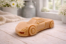 Load image into Gallery viewer, handmade vegan soap in the shape of a sleek supercar sculpture, featuring aerodynamic curves and detailed wheels, displayed on a rustic white wooden surface in a bright farmhouse decor setting.