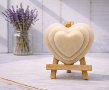 Load image into Gallery viewer, handmade vegan soap gift featuring a triple-tiered heart relief design, displayed on a wooden easel against a rustic farmhouse decor background with lavender.
