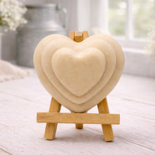 Load image into Gallery viewer, handmade vegan soap gift featuring a triple-tiered heart relief design, displayed on a wooden easel against a rustic farmhouse decor background with lavender.