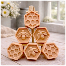 Load image into Gallery viewer, A handmade vegan soap gift set featuring six hexagonal bars stacked in a pyramid on a small wooden easel; some bars show a honeybee relief and others a honeycomb pattern