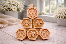Load image into Gallery viewer, A handmade vegan soap gift set featuring six hexagonal bars stacked in a pyramid on a small wooden easel; some bars show a honeybee relief and others a honeycomb pattern