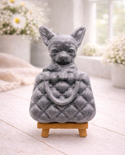 Load image into Gallery viewer, A highly detailed handmade vegan soap in a speckled grey marble finish, sculpted as a small chihuahua puppy with large ears peeking out from inside a quilted designer-style handbag, displayed on a miniature wooden easel.