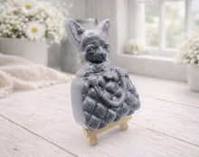 Load image into Gallery viewer, A highly detailed handmade vegan soap in a speckled grey marble finish, sculpted as a small chihuahua puppy with large ears peeking out from inside a quilted designer-style handbag, displayed on a miniature wooden easel.