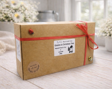 Load image into Gallery viewer, Kraft paper box with red ribbon on a wooden surface with blurred flowers in the background