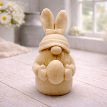 Load image into Gallery viewer, A detailed handmade vegan soap in a natural colour, sculpted as a whimsical Easter gnome (gonk) with long rabbit ears and a bow on its hat, holding a patterned Easter egg, displayed on a light wooden surface. Easter gift