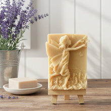 Load image into Gallery viewer, A rectangular handmade vegan soap featuring a detailed relief of a winged fairy reaching towards a butterfly in a meadow of tall grass and flowers, displayed on a miniature wooden easel