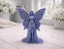 Load image into Gallery viewer, A detailed handmade vegan soap featuring an elegant fairy with large, intricate butterfly-style wings, a flowing gown, and long hair, standing against a bright farmhouse window background.