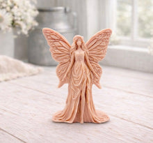 Load image into Gallery viewer, A detailed handmade vegan soap featuring an elegant fairy with large, intricate butterfly-style wings, a flowing gown, and long hair, standing against a bright farmhouse window background.