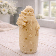 Load image into Gallery viewer, handmade vegan soap sculpted into a tall figure of Father Christmas wearing star-patterned robes, holding a small Christmas tree in one arm and a lantern in the other, set in a bright farmhouse window.