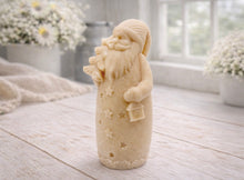 Load image into Gallery viewer, handmade vegan soap sculpted into a tall figure of Father Christmas wearing star-patterned robes, holding a small Christmas tree in one arm and a lantern in the other, set in a bright farmhouse window.