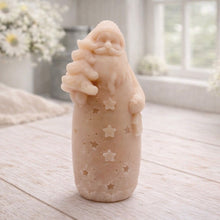 Load image into Gallery viewer, handmade vegan soap sculpted into a tall figure of Father Christmas wearing star-patterned robes, holding a small Christmas tree in one arm and a lantern in the other, set in a bright farmhouse window.