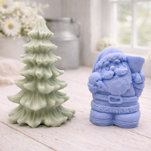 Load image into Gallery viewer, A duo of handmade vegan soaps featuring a Father Christmas figure with standing next to a mint-green tiered 3D Christmas tree, displayed in a bright farmhouse setting.
