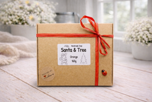 Load image into Gallery viewer, Gift box with 'Santa & Tree' label and red ribbon on a wooden surface