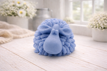 Load image into Gallery viewer, A highly detailed handmade vegan soap sculpted in the shape of a fluffy sheep with thick, textured wool and a smooth face, displayed on a light wooden surface in a farmhouse-style setting.