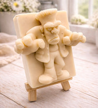 Load image into Gallery viewer, A rectangular handmade vegan soap featuring a high-relief carving of Frankenstein's monster in a classic pose with arms outstretched and a grumpy expression, displayed on a miniature wooden easel.