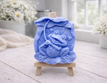 Load image into Gallery viewer, A rectangular handmade vegan soap featuring a high-relief carving of a cheerful, smiling frog sitting on a large lilypad and holding the stem of a leaf over its head like an umbrella.