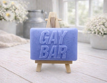 Load image into Gallery viewer, A rectangular handmade vegan soap featuring the words "GAY BAR" in large, bold, 3D block lettering, displayed on a miniature wooden easel.