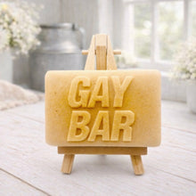 Load image into Gallery viewer, A rectangular handmade vegan soap featuring the words "GAY BAR" in large, bold, 3D block lettering, displayed on a miniature wooden easel.
