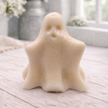 Load image into Gallery viewer, A handmade vegan soap shaped like a friendly ghost with a surprised expression, sitting on a light wood surface with white daisies in the background