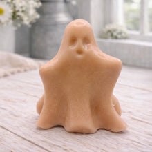 Load image into Gallery viewer, A handmade vegan soap shaped like a friendly ghost with a surprised expression, sitting on a light wood surface with white daisies in the background