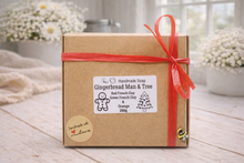 Load image into Gallery viewer, Handmade soap packaging with a gingerbread man and tree design on a wooden surface.