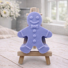 Load image into Gallery viewer, A handmade vegan featuring a classic gingerbread man with a smiling face, a bow tie, and decorative icing details on his arms and legs, displayed on a miniature wooden easel.