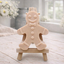 Load image into Gallery viewer, A handmade vegan featuring a classic gingerbread man with a smiling face, a bow tie, and decorative icing details on his arms and legs, displayed on a miniature wooden easel.