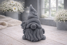 Load image into Gallery viewer, A 3D handmade vegan soap in a warm cream tone, sculpted into a cute garden gnome or gonk with a long flowing beard, a large round nose, and a tall pointed hat adorned with small embossed flowers.