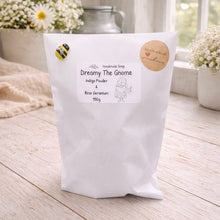 Load image into Gallery viewer, White bag of handmade soap labeled 'Dreamy The Gnome' on a wooden surface with flowers in the background.