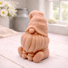 Load image into Gallery viewer, A handmade vegan soap in a natural tone, sculpted as a gnome (gonk) with a tall, curved hat that covers the eyes and has clouds on it, a round nose, and a long, textured beard.