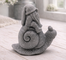 Load image into Gallery viewer, A handmade vegan soap gift, sculpted as a whimsical gnome (gonk) with a tall, slouchy hat and a long beard, sitting on the shell of a large snail with a textured, bumpy body.