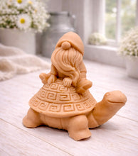 Load image into Gallery viewer, A handmade vegan soap in a natural tone, sculpted as a whimsical gnome (gonk) with a long beard sitting on the back of a large, smiling turtle with a patterned geometric shell.
