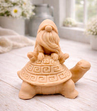 Load image into Gallery viewer, A handmade vegan soap in a natural tone, sculpted as a whimsical gnome (gonk) with a long beard sitting on the back of a large, smiling turtle with a patterned geometric shell.