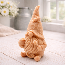 Load image into Gallery viewer, A handmade vegan soap in the shape of a gnome with a long beard, wearing a honeycomb-patterned hat with a bee, holding a honey pot and dipper.