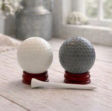 Load image into Gallery viewer, A handmade vegan golf ball soap gift set featuring one white and one grey spherical soap with realistic dimpled textures, displayed on small wooden stands next to a white golf tee and a kraft gift box tied with a red ribbon
