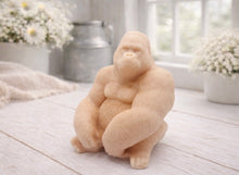 Load image into Gallery viewer, A highly detailed handmade vegan soap in a natural colour, sculpted in the shape of a sitting gorilla with realistic fur and muscle textures, displayed on a light wooden surface.