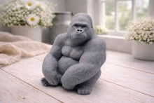 Load image into Gallery viewer, A highly detailed handmade vegan soap in a natural stone-grey colour, sculpted in the shape of a sitting gorilla with realistic fur and muscle textures, displayed on a light wooden surface.