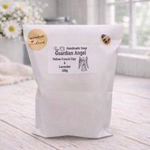 Load image into Gallery viewer, Handmade soap packaging labeled 'Guardian Angel' on a wooden surface with flowers in the background.