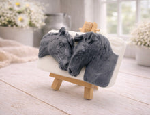 Load image into Gallery viewer, A rectangular handmade vegan soap featuring a detailed 3D relief of two horse heads leaning affectionately towards each other, finished in a slate-grey tone against a white soap base and displayed on a miniature wooden easel.