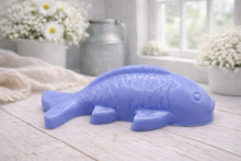 Load image into Gallery viewer, Handmade vegan soap sculpted in the shape of a koi carp fish with detailed scales and fins, resting on a light timber surface with a soft floral background.
